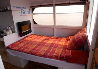 Doppelbett mit Elektrokamin im Mini-Hausboot